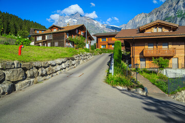 Fototapeta na wymiar Charming wooden homes and high mountains in background, Grindelwald, Switzerland