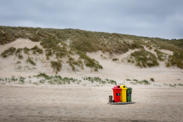 Garbage bin on the beach, Beach and dunes desolate nobody  only three colorful trash cans red yellow and green