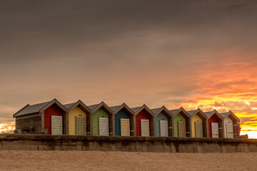 The vibrant and colorful beach huts by the promenade overlooking Blyth beach with a lovely sunset in Northumberland, England
