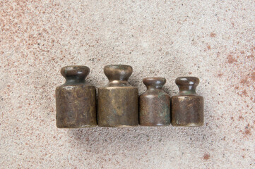 Four antique bronze weights for scales on concrete background.