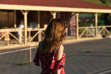 Woman in red dress walking  in the street from the back