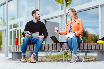 Man and woman student chatting on university campus in front of main building