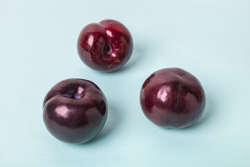 Three large plums on a blue background. Delicious berry for dessert.