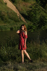 Fototapeta premium Slender woman in summer dress standing near the lake
