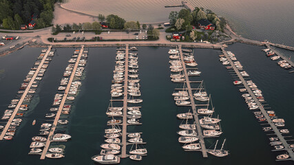 Aerial top view of a lot of white yachts and sailboats moored in a marina, summer season