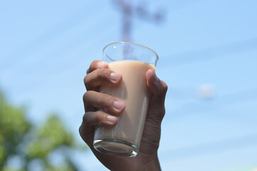Man hand holding Iced Milk Tea in the glass refreshing look with blurred background. selective focus