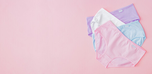 Flat lay set of women panties of different colors on a pink background. Top view advertising and shopping concept