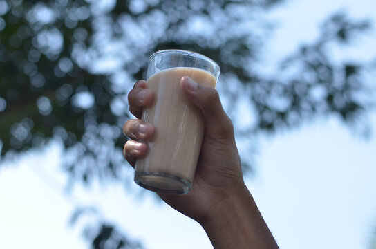 Man hand holding Iced Milk Tea in the glass refreshing look with blurred background. selective focus