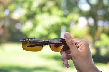 man hand holding Black Glasses or sun glasses with vintage style and blurred background