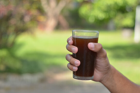 male hand holding Iced Coffee in the glass refreshing look with blurred background. selective focus