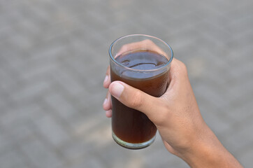 male hand holding Iced Coffee in the glass refreshing look with blurred background. selective focus