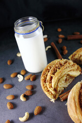 puff golden delicious bun with sugar and cinnamon on a dark background. Fresh milk in a jar with cinnamon sticks and almonds. Rustic style. Home cooking. Photos for the menu