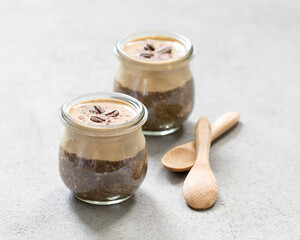 Obraz na płótnie Canvas Dessert in a glass jar, coffee pudding chia seeds with cottage cheese cream on light background