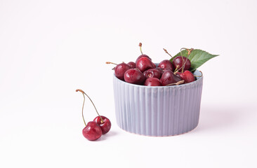 juicy red cherries in a gray bowl on a pink background. Front view and copy space