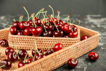 Cherry red in a wicker basket on a dark background.