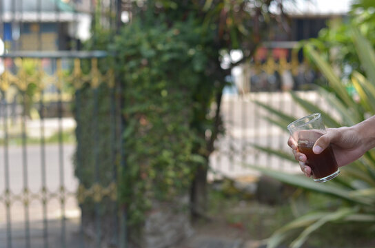 male hand holding Iced Coffee in the glass refreshing look with blurred background. selective focus