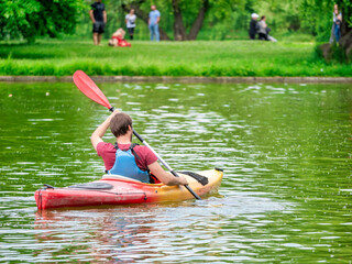 Man in a kayak paddling in Titan Park or Alexandru Ioan Cuza park. Man canoeing on a lake in...