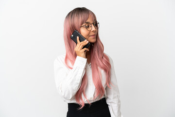 Young business mixed race woman with pink hair holding a mobile isolated on pink background looking to the side