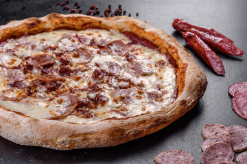 Fresh delicious Italian pizza with four types of meat on a dark concrete background