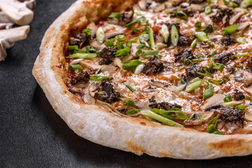 Fresh delicious Italian pizza with meat, mushrooms and tomatoes on a dark concrete background