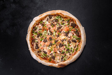 Fresh delicious Italian pizza with meat, mushrooms and tomatoes on a dark concrete background