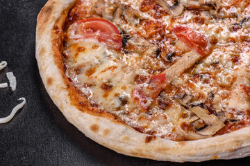 Fresh delicious Italian pizza with mushrooms and tomatoes on a dark concrete background