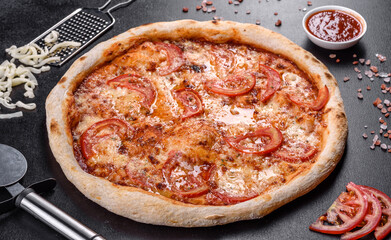 Fresh delicious Italian pizza with mushrooms and tomatoes on a dark concrete background