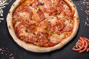Fresh delicious Italian pizza with mushrooms and tomatoes on a dark concrete background