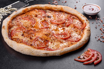 Fresh delicious Italian pizza with mushrooms and tomatoes on a dark concrete background