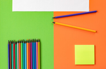 Minimum set of school and office supplies on bright orange and green background: multicolor...