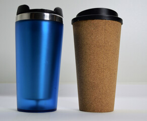 textured decorative light brown hot drink glass with black plastic lid blue hot drink glass with transparent walls silver rim and black lid on a white background