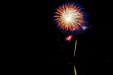 Holiday fireworks above water with reflection in the water