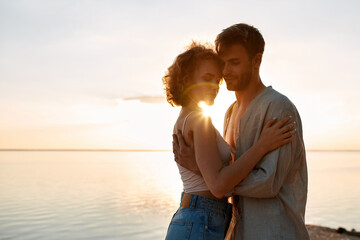 Sensual young caucasian couple embracing at sunset
