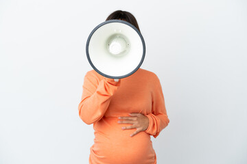 Young mixed race pregnant woman isolated on white background shouting through a megaphone to announce something