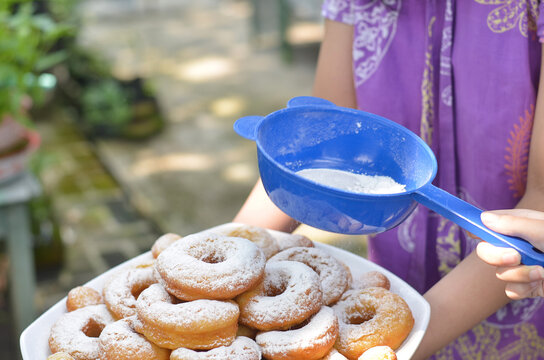 woman's hand sprinkles sugar topping on a donuts with blurred background