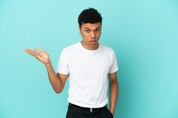 Young African American man isolated on blue background making doubts gesture