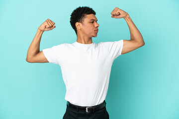 Young African American man isolated on blue background doing strong gesture