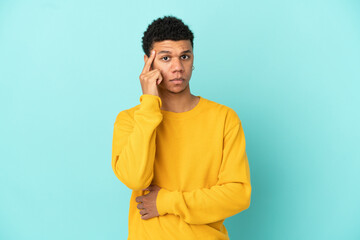 Young African American man isolated on blue background thinking an idea