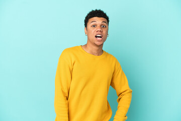 Young African American man isolated on blue background with surprise facial expression