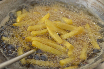 hand frying french fries in the frying pan