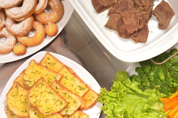 Western Food Dish Background with garlic bread, donuts, vegetables and slices beef steak