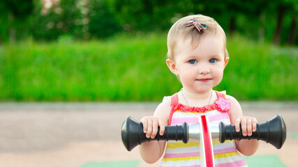 little funny baby girl smiling and swinging on swing on playground. happy kid outdoors at park summer. Copyspace