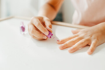 Six year preschooler girl with interest paint on nails with nail polish