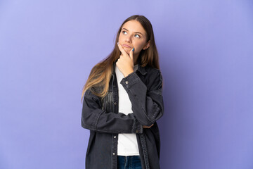 Young Lithuanian woman isolated on purple background having doubts