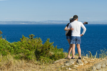 Fototapeta premium friends looking on a cliff above the sea, hikers looking at view and enjoying enjoy climbing to the top. Active lifestyle.