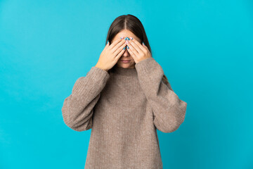 Young Lithuanian woman isolated on blue background covering eyes by hands