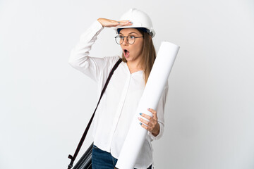 Young Lithuanian architect woman with helmet and holding blueprints isolated on white background doing surprise gesture while looking to the side