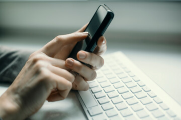 A hand dials on a smartphone in the office, close-up.
