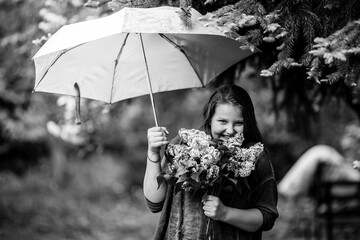 A girl in the park with a bouquet under an umbrella. Black and white photo.