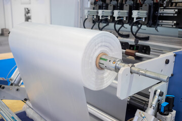 Moving roller with flat polyethylene transparent film - automatic plastic bag making machine at...